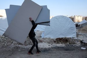Des personnes sans abri suite au séisme de magnitude 7,8 qui a frappé la Turquie et la Syrie le 6 février 2023, reçoivent des matelas distribués par une ONG, dans un camp de la ville d'Afrin, dans la province d'Alep tenue par les rebelles, le 16 février 2023