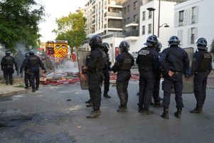 Des policiers en tenue anti-émeute montent la garde tandis que des pompiers s'efforcent d'éteindre des incendies après une manifestation à Nanterre, à l'ouest de Paris, le 27 juin 2023.