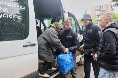 Des bénévoles du Fonds caritatif Khaustov aident une femme âgée, évacuée d’une zone proche de la ligne de front, à sortir d’une camionnette, Kharkiv, Ukraine, le 12 mai 2025.
