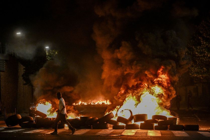 Un homme marche à côté de pneus en feu bloquant une rue à Bordeaux le soir du 29 juin 2023, alors que la France est agitée par des émeutes urbaines.